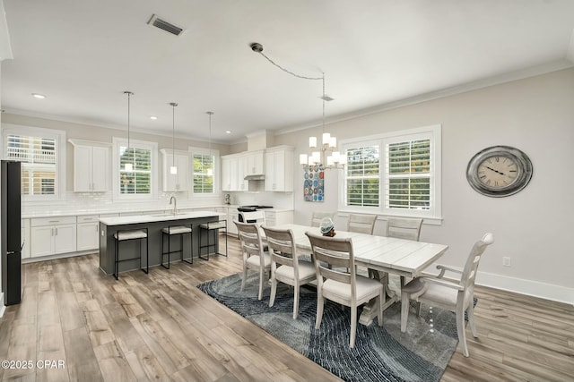 19 Mckenna Way, Santa Rosa Beach, FL 32459 - dining room with ornamental molding, light wood-style flooring, and a notable chandelier