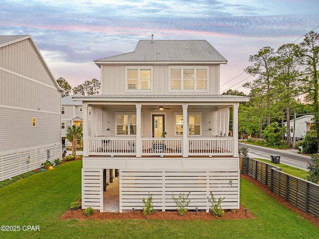 19 Mckenna Way, Santa Rosa Beach, FL 32459 - back of property at dusk with a porch, metal roof, a lawn, board and batten siding, and fence
