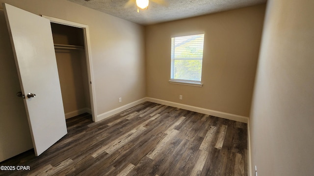 unfurnished bedroom with dark wood finished floors, a textured ceiling, a closet, and baseboards