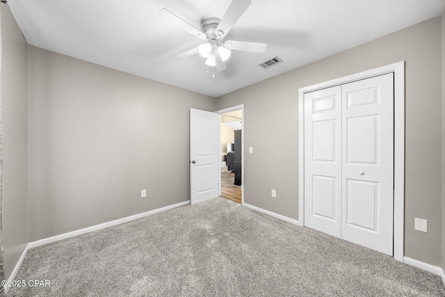 unfurnished bedroom with carpet floors, visible vents, a closet, baseboards, and ceiling fan