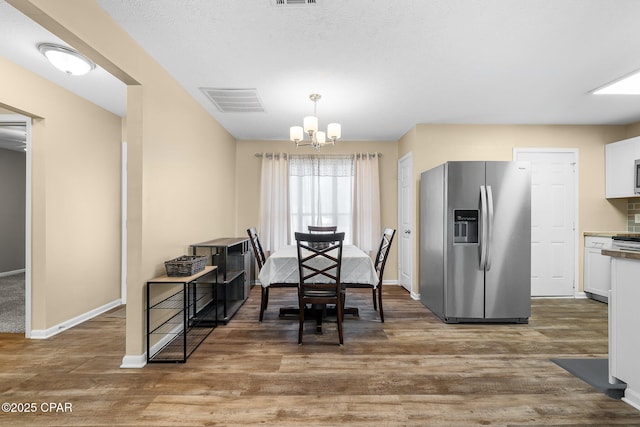 dining room featuring visible vents, light wood-style floors, baseboards, and an inviting chandelier
