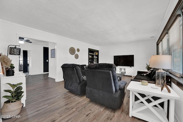 living area with a textured ceiling, wood finished floors, a ceiling fan, and baseboards