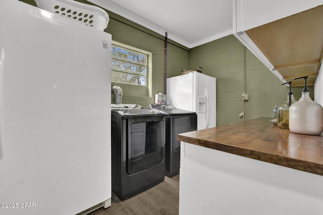 kitchen featuring light wood-style flooring, washing machine and dryer, freestanding refrigerator, butcher block counters, and concrete block wall