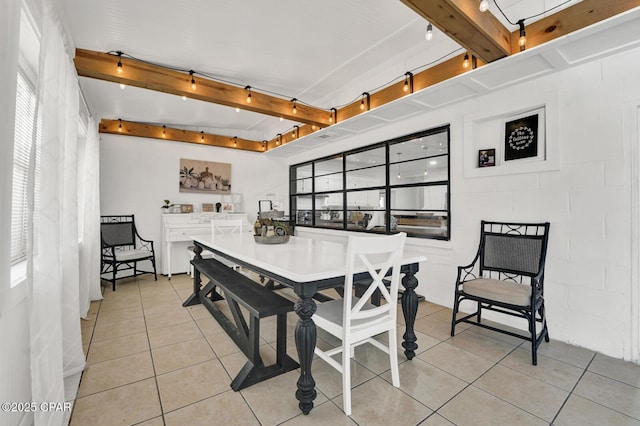 dining space with track lighting, light tile patterned floors, and beamed ceiling