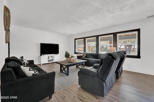 living room featuring a textured ceiling, wood finished floors, visible vents, and baseboards