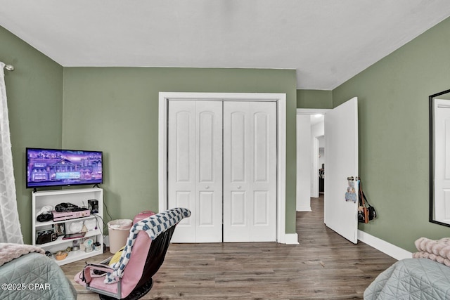 bedroom with baseboards, wood finished floors, and a closet