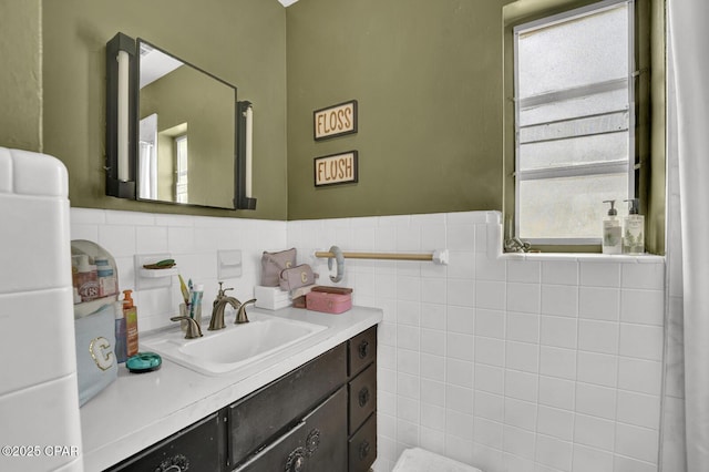 bathroom featuring tile walls, wainscoting, vanity, and plenty of natural light