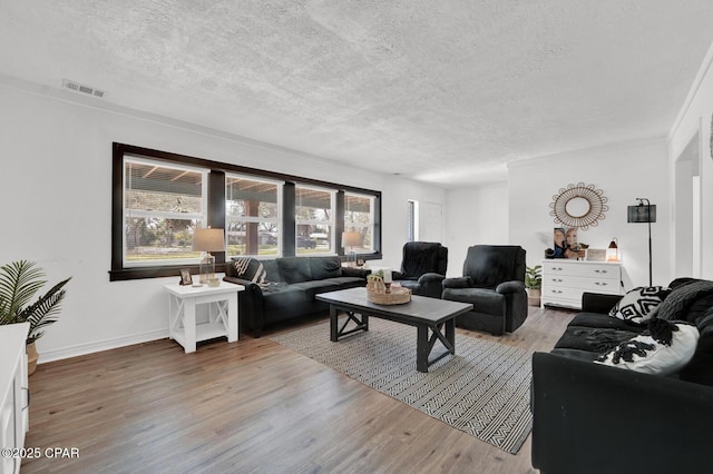 living room featuring visible vents, a healthy amount of sunlight, a textured ceiling, and light wood-style flooring