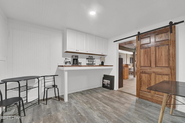 kitchen featuring wood finished floors, a barn door, and white cabinetry