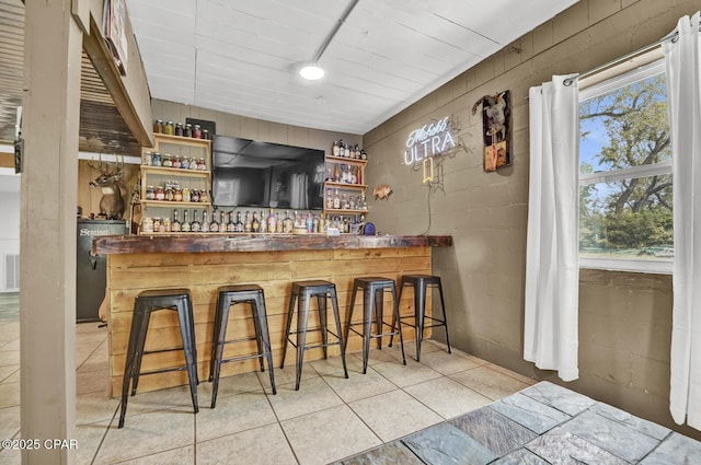 bar with concrete block wall, a dry bar, tile patterned floors, and visible vents