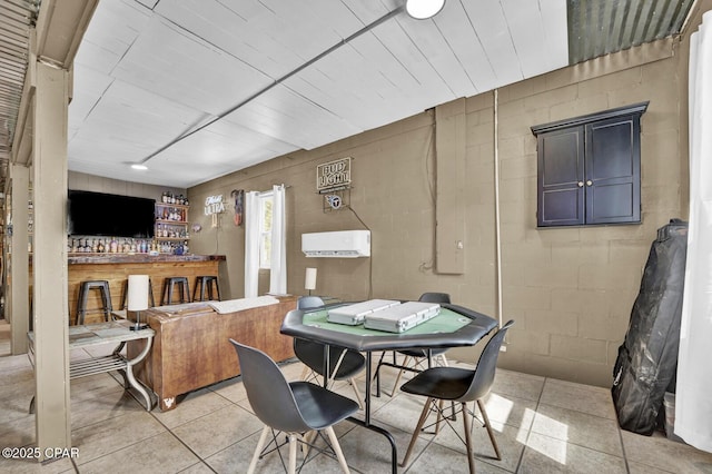 dining space with a dry bar, light tile patterned floors, and concrete block wall