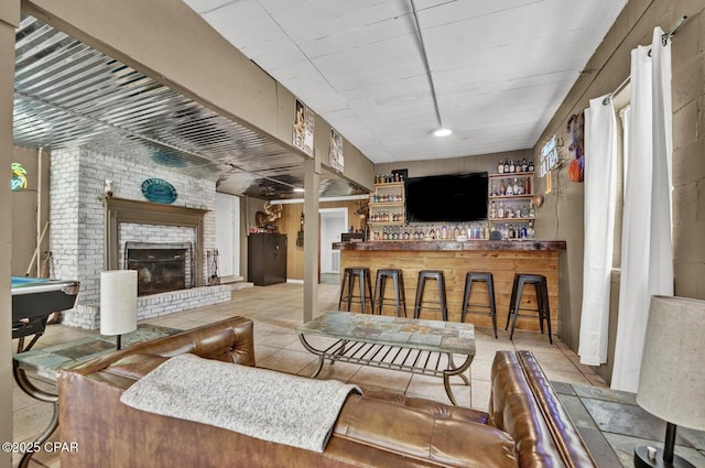 tiled living area with pool table, a brick fireplace, and a dry bar