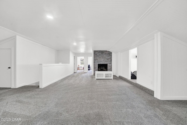 unfurnished living room featuring lofted ceiling, carpet, and a brick fireplace