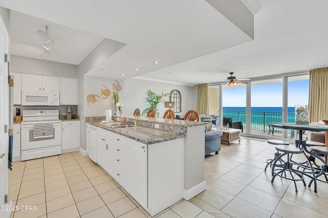 14701 Front Beach Rd Unit 834, Panama City Beach, FL 32413 - kitchen featuring white appliances, a peninsula, a sink, light tile patterned floors, and white cabinetry