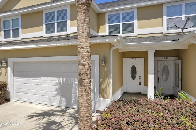 view of front of property featuring a garage, roof with shingles, stucco siding, and concrete driveway