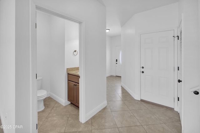bathroom featuring tile patterned flooring, baseboards, toilet, and vanity