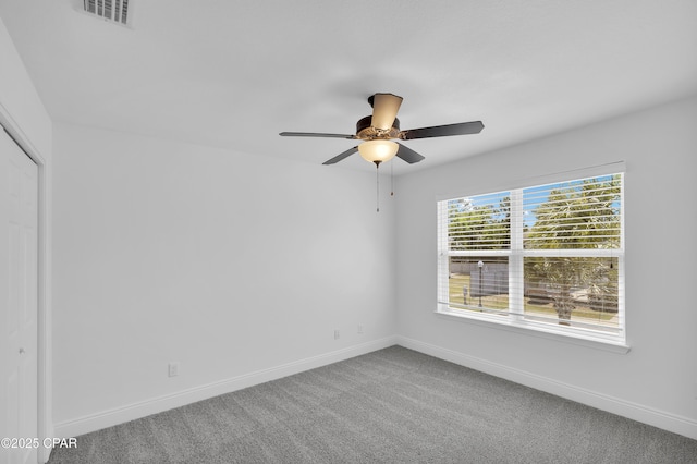 carpeted empty room with baseboards, ceiling fan, and visible vents