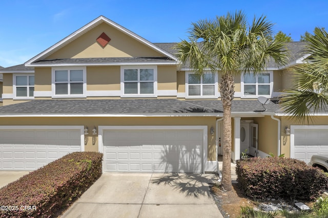 view of property with an attached garage, a shingled roof, stucco siding, and driveway