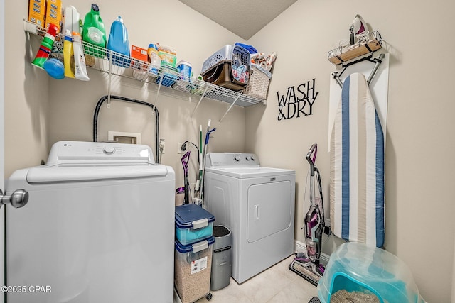 clothes washing area with separate washer and dryer, laundry area, and tile patterned flooring