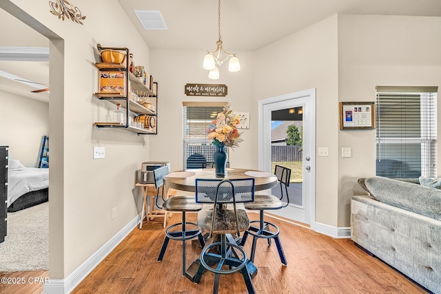 dining room with an inviting chandelier, baseboards, wood finished floors, and visible vents