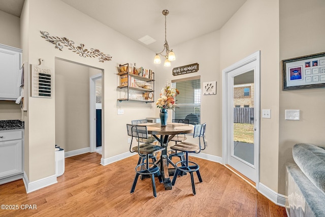 dining room with baseboards, a notable chandelier, and light wood-style flooring