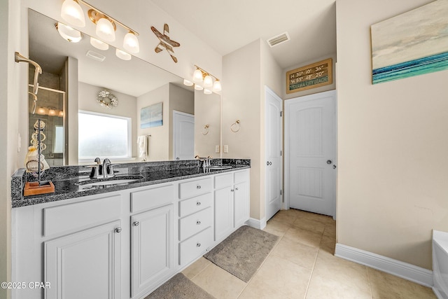 bathroom with double vanity, baseboards, a sink, and tile patterned floors