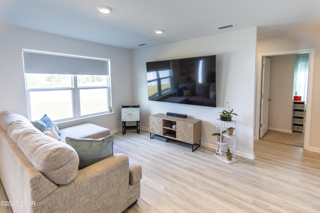 living room with visible vents, plenty of natural light, and light wood-type flooring