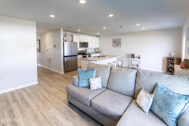 living room featuring baseboards, recessed lighting, and light wood-style flooring
