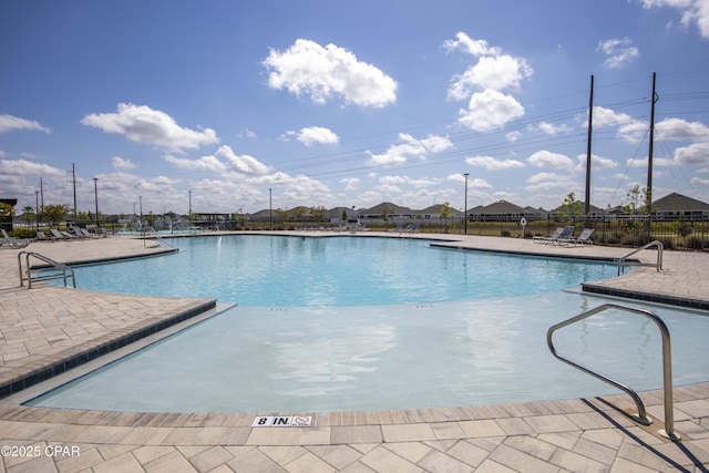 community pool with a patio area and fence