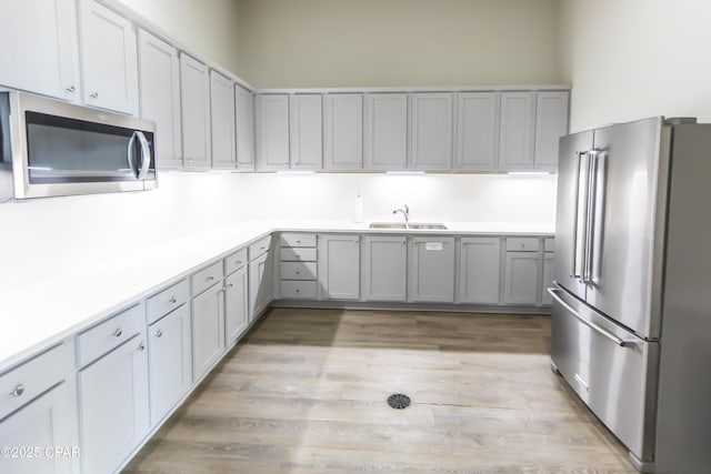 kitchen with light countertops, stainless steel appliances, a sink, and light wood-style flooring