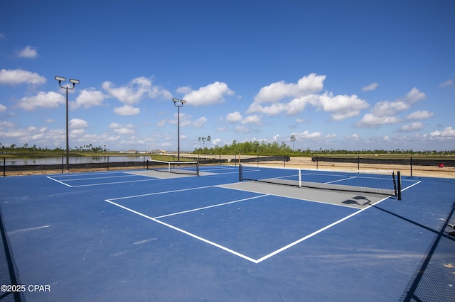 view of sport court featuring a water view, fence, and community basketball court
