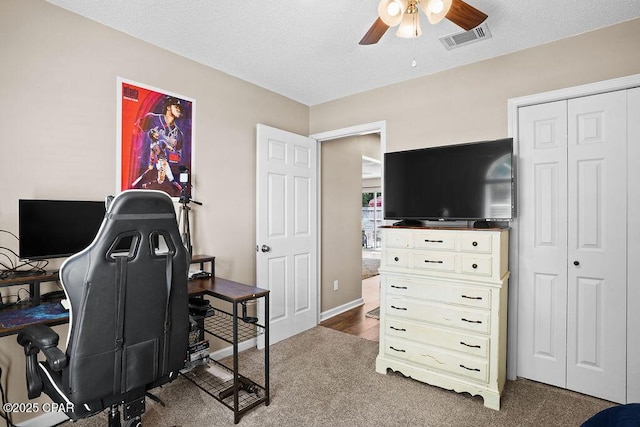 home office with carpet flooring, a textured ceiling, visible vents, and ceiling fan