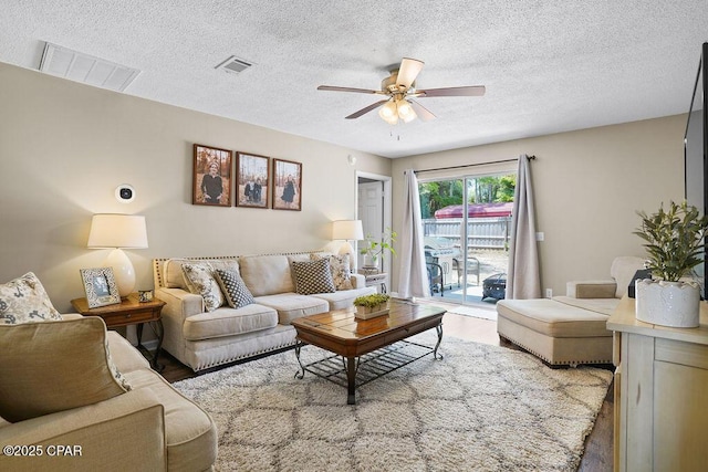 living room featuring a textured ceiling, visible vents, and wood finished floors