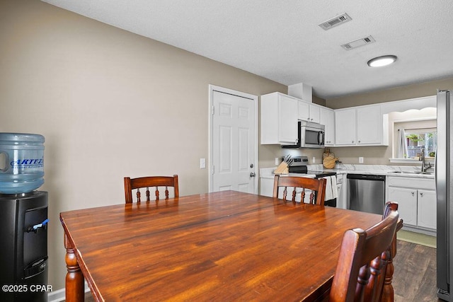 dining room with a textured ceiling, visible vents, and wood finished floors
