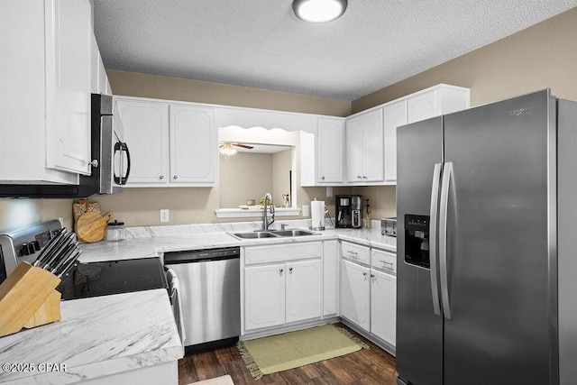 kitchen with a sink, white cabinets, dark wood finished floors, light countertops, and appliances with stainless steel finishes