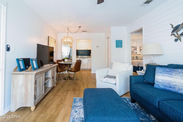 living room featuring visible vents, an inviting chandelier, and light wood-type flooring