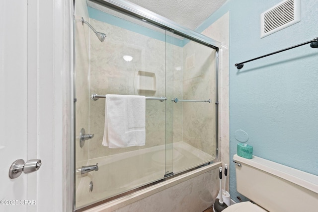 8743 Thomas Dr Unit 809, Panama City Beach, FL 32408 - full bath with shower / bath combination with glass door, a textured ceiling, toilet, and a textured wall