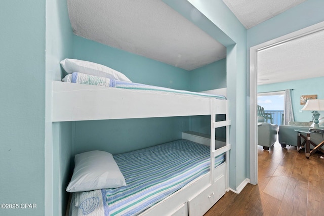 8743 Thomas Dr Unit 809, Panama City Beach, FL 32408 - bedroom featuring a textured ceiling, wood finished floors, and baseboards