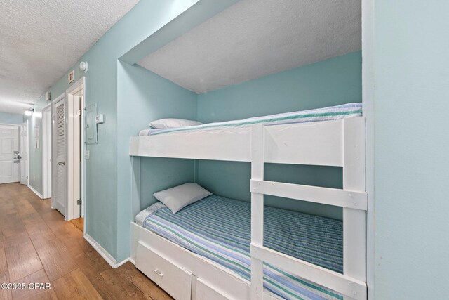 8743 Thomas Dr Unit 809, Panama City Beach, FL 32408 - bedroom with a textured ceiling, wood finished floors, and baseboards