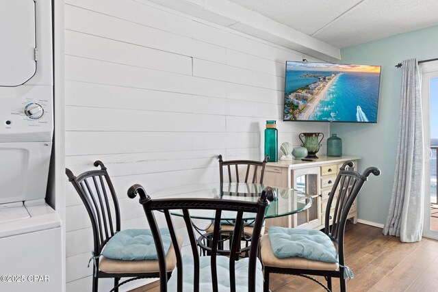 8743 Thomas Dr Unit 809, Panama City Beach, FL 32408 - dining area with stacked washer / dryer, wood finished floors, baseboards, wood walls, and a textured ceiling