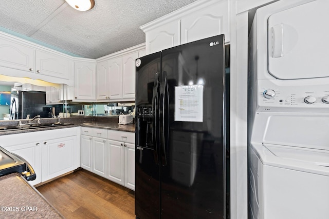 8743 Thomas Dr Unit 809, Panama City Beach, FL 32408 - kitchen with black refrigerator with ice dispenser, estacked washer and dryer, white cabinetry, dark wood finished floors, and dark countertops