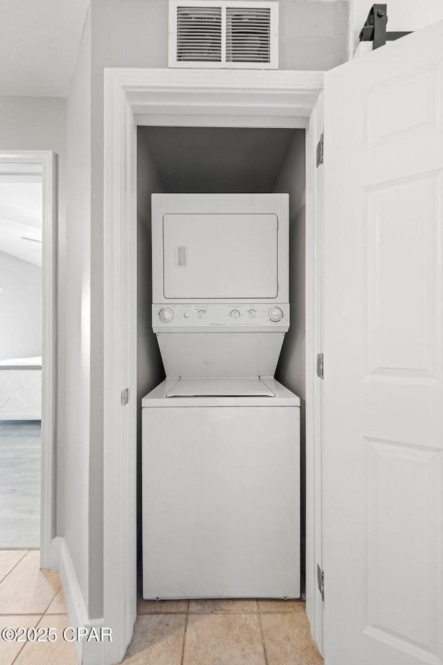 9860 S Thomas Dr Unit 1018, Panama City Beach, FL 32408 - laundry room featuring estacked washer and dryer, light tile patterned floors, and baseboards
