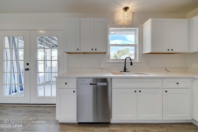 kitchen with light stone countertops, wood finished floors, dishwasher, a sink, and white cabinetry
