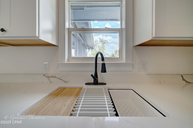 details with a sink, white cabinetry, and light countertops