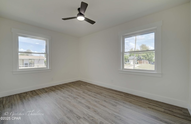 spare room with baseboards, ceiling fan, and wood finished floors