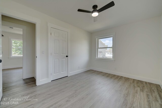 unfurnished bedroom featuring a ceiling fan, baseboards, and light wood-type flooring