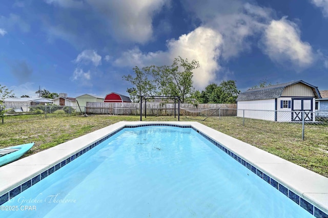 view of pool featuring a fenced backyard, a shed, a fenced in pool, a lawn, and an outbuilding
