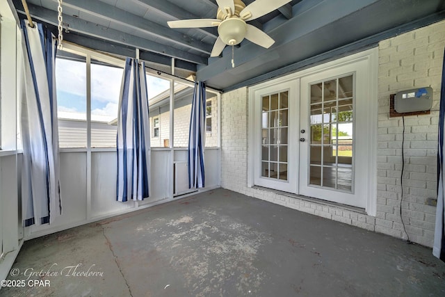exterior space featuring concrete flooring, ceiling fan, french doors, and brick wall