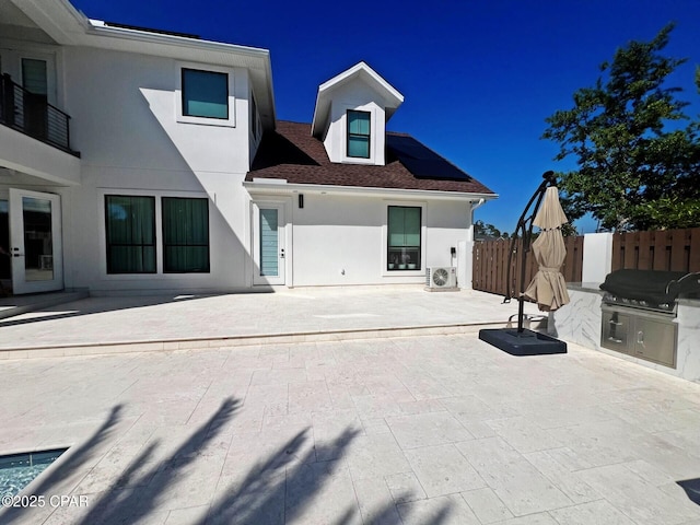 3639 Preserve Blvd, Panama City Beach, FL 32408 - exterior space featuring fence, roof with shingles, stucco siding, roof mounted solar panels, and a patio area