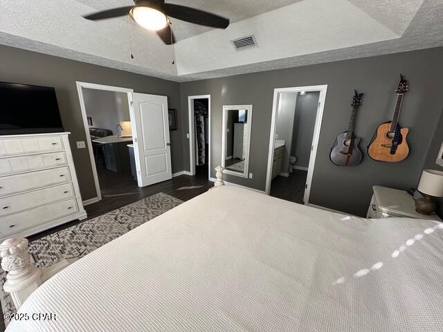 bedroom with baseboards, ensuite bathroom, a closet, and a walk in closet